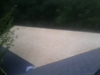 New OSB roof sheathing installed beside an existing shingle roof in Byron