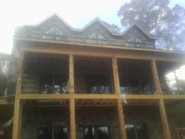 Dormers and porch framing on a large log home under construction — Roof Coating work by our crew in Byron